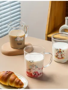 Close-up detail of clear glass scale milk cup with cute cartoon unicorn and pig print.