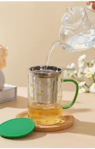 Close-up detail of heat-resistant glass tea mug with stainless steel infuser and green handle.
