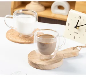 Nahaufnahme des doppelwandigen Glas-Kaffeebechers mit praktischem Henkel auf Holzuntersetzer.