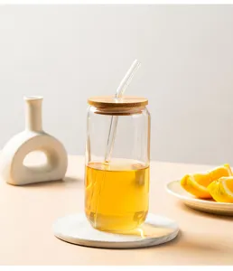 Detailed view of the clear glass tumbler with bamboo lid and glass straw, lifestyle setting.