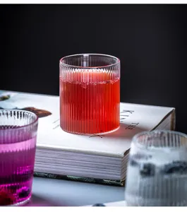 Gedetailleerde close-up van geribbeld glazen beker met kleurrijke drank op rustiek boek
