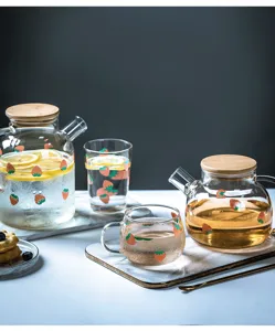 Grazioso set di tazze in vetro con fragole e teiera con coperchio in legno per succhi.