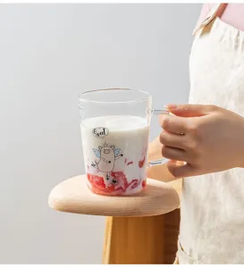 Detailed view of clear glass milk cup with cute cartoon pig and measurement scale for home.