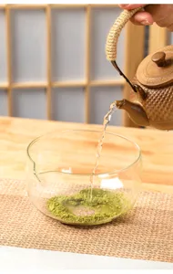 Detail shot of a clear hammered glass matcha bowl with pouring spout, hot water being added.