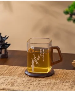 Detail shot of square glass tea cup with wooden handle and coaster, clear heat-resistant drinkware.