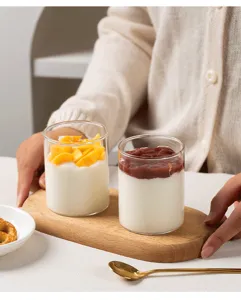 Tasses à yaourt en verre transparent avec planche en bois pour présentation de dessert en détail.