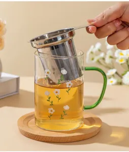 Stainless steel tea infuser filter basket detail view inside clear glass tea cup.