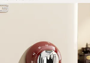 Close-up detail of a red mechanical kitchen timer with silver dial, magnetic accessory.