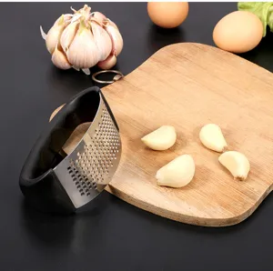 Stainless steel curved garlic press detail, ergonomic black plastic handle, kitchen tool for garlic mincing.