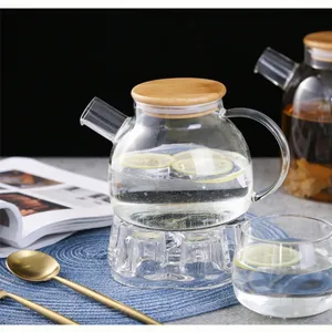 Clear glass teapot detail shot with wooden lid and lemon water on table setting.