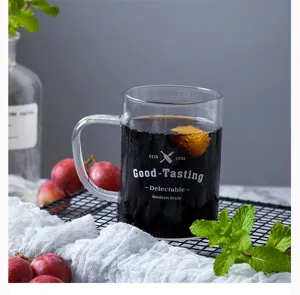 Detail shot of clear glass mug with handle, printed text, and refreshing cold beverage setup.