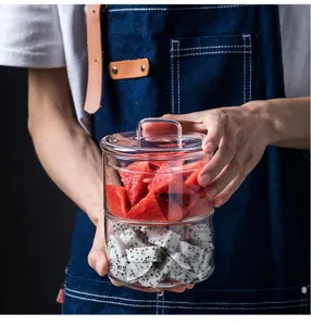 Vue rapprochée d'un pot de stockage en verre transparent avec couvercle, rempli de fruits frais.