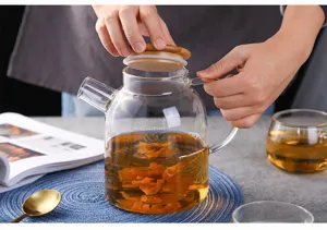 Clear glass teapot with wooden lid for blooming scented tea, heat-resistant glassware.