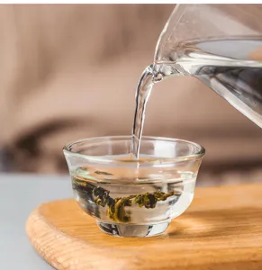 Close-up detail of heat-resistant glass tea cup showing pouring water process during tea ceremony.
