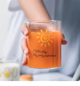 Detailed close-up shot of the clear glass cup featuring cute sun print and lovely english quotes.