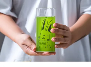 Clear glass square cup with cute cartoon rabbit print and green drink, perfect for daily use.
