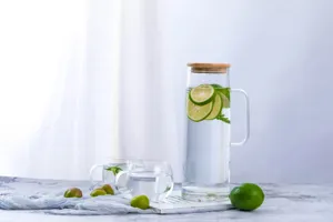 Détail de pichet à eau en verre avec corps transparent et couvercle en bambou naturel.