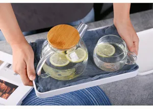 Clear glass teapot and cup set with natural bamboo lid, ideal for brewing fruit tea and water.