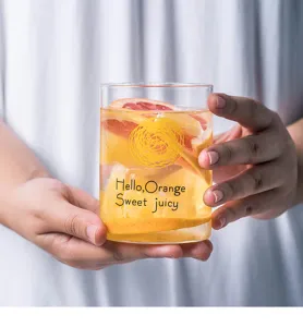 Detailed view of a transparent glass cup holding fresh fruit and cute text print design.