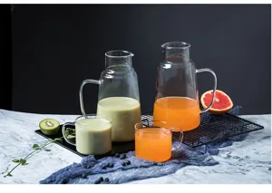 Détail d'un ensemble pichet et tasses en verre résistant à la chaleur, idéal pour jus et thé.