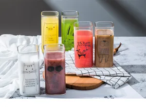 Close-up detail of creative square glass cups with cute animal prints and colorful drinks.