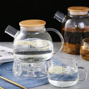 Clear glass teapot set with bamboo lid and warmer base, perfect for brewing fruit tea daily.