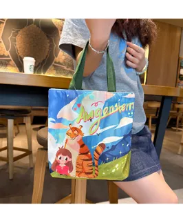 Canvas tote bag detail showing cute illustration, green handles and portable lunch box design.