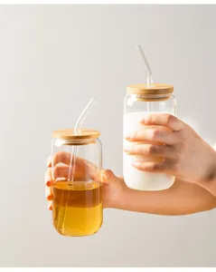 Close-up detail of glass can cups with bamboo lids and straws, showcasing design.