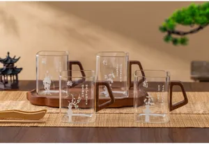 Detail view of Chinese style heat-resistant glass tea cup with wooden handle and plum design.