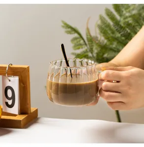 Detail view of a clear ribbed glass pumpkin cup with coffee, lifestyle scene with wooden prop.