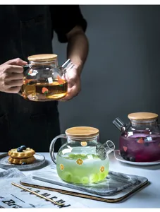 Teiera in vetro con coperchio in legno e motivi di frutta, ideale per succhi e tè quotidiani.