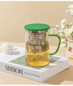 Detailed view of heat-resistant glass tea cup with infuser, green lid and floral pattern.