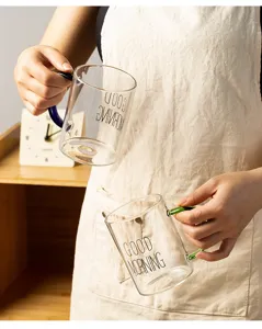 Clear glass coffee mug with colorful handle and letter print for home breakfast use.