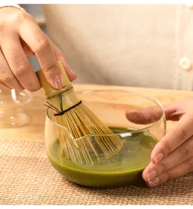 Handcrafted bamboo matcha whisk and glass bowl set for traditional tea preparation detail.