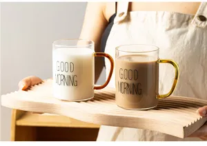 Clear glass coffee mug featuring colored handle and printed morning text close up detail.