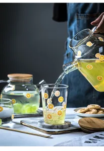 Set di tazze e brocche in vetro con frutta, stoviglie trasparenti per acqua, succo e bevande.