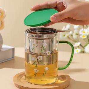 Heat resistant glass tea mug with stainless steel infuser and green lid for office use.