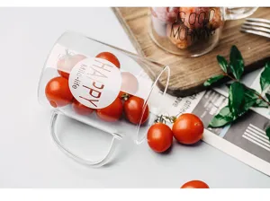 Detaillierte Nahaufnahme einer transparenten Glastasse mit frischen Kirschtomaten auf einem Holzbrett.
