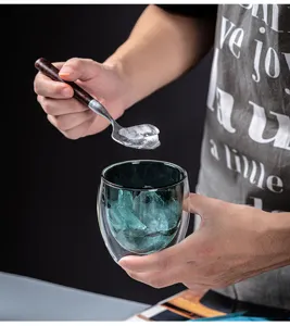 Creative double wall glass cup detail shot with ice cubes and wooden handle spoon for home.