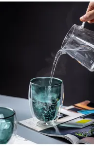 Detail shot of double wall glass cup showing heat insulation feature and water pouring