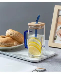 Square glass water cup detail view, clear design with wooden lid and blue glass straw.