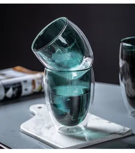 Close-up detail of double wall insulated glass cup with ice water, elegant teal design kitchenware.