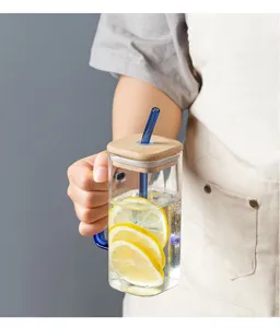 Detailed shot of square glass cup with wooden lid, handle and straw, crystal clear daily drinkware.