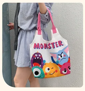 Close up detail view of cute cartoon monster print canvas tote bag, large capacity shoulder bag.