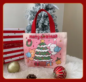 Vue détaillée d'un sac cabas en toile rose de Noël avec motifs de dessins et poignées.