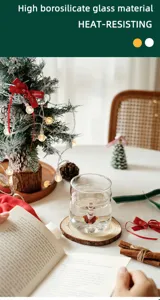 Detail shot of cute Christmas glass cup featuring 3D holiday figurine on wooden coaster.