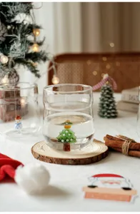 Detail view of clear glass cup with 3D Christmas tree inside, holiday tabletop decor prop.