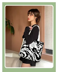 Black and white abstract fluid print canvas tote bag detail showing shoulder strap and patch.