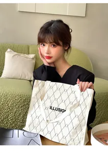 Detailed view of large canvas tote bag with diamond lattice pattern and letter print for daily use.