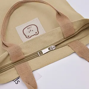 Cute canvas handbag for women, casual tote bag with zipper and cartoon bear patch.